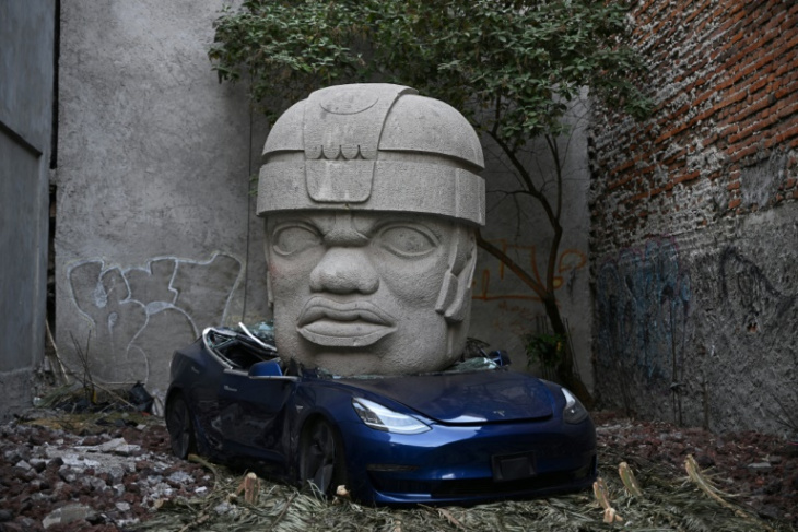 un tesla aplastado por una colosal escultura indígena, el provocador arte urbano en méxico